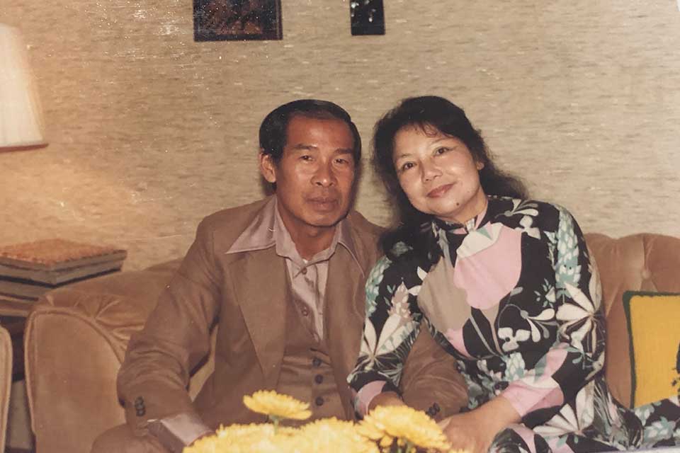 A photograph of Lam's parents in their thirties sitting on a couch typical of the 1970s